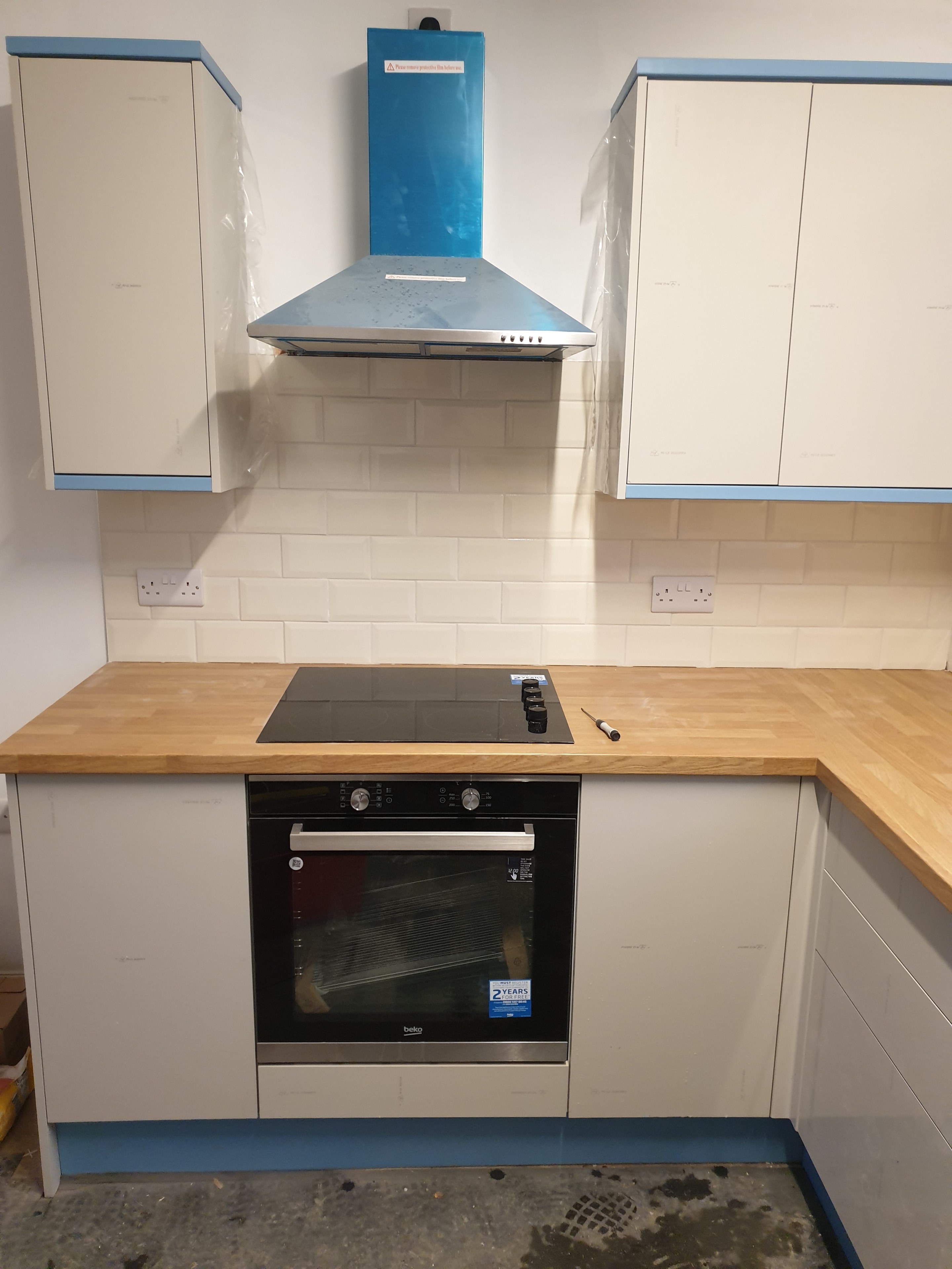 Kitchen with light cabinetry, timber worktops and white subway tiles, finished with a black oven and hob.