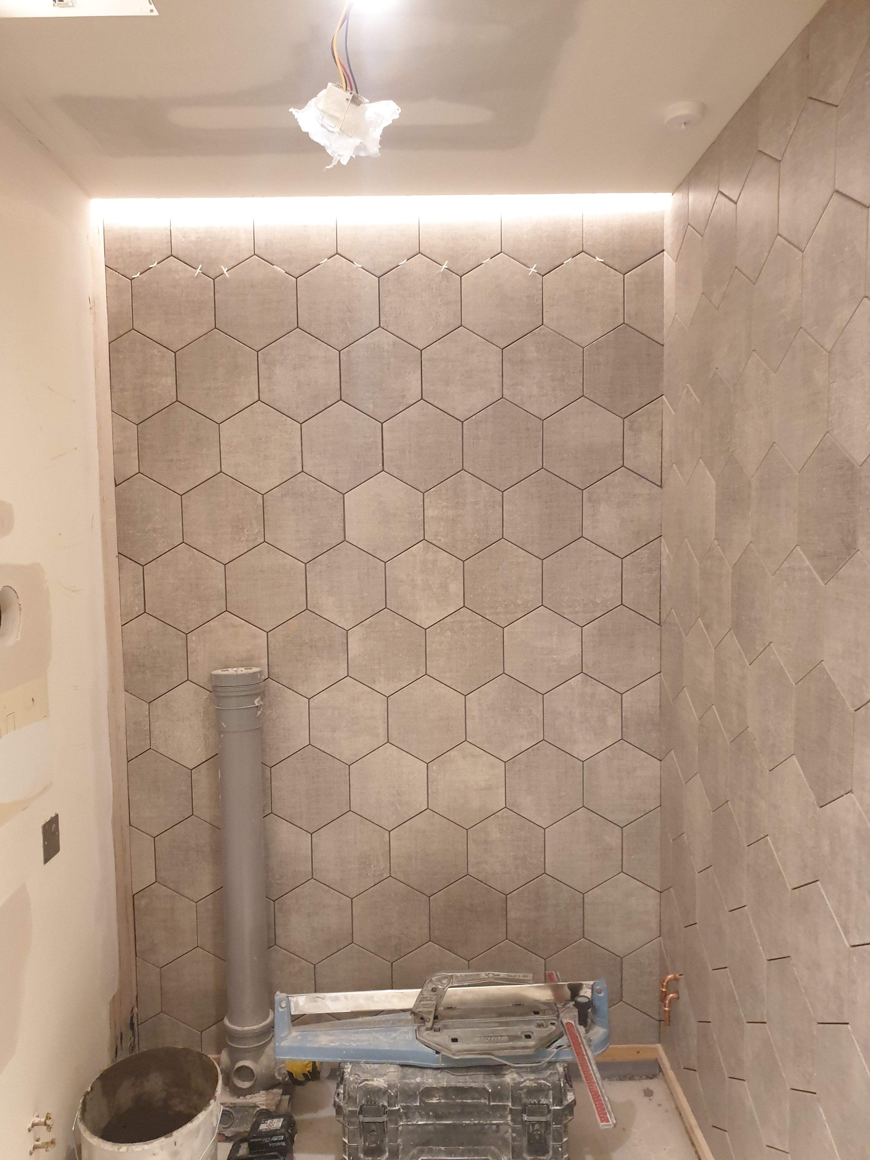 Tiling in progress, combining hexagonal feature tiles with a herringbone pattern on the adjoining wall.