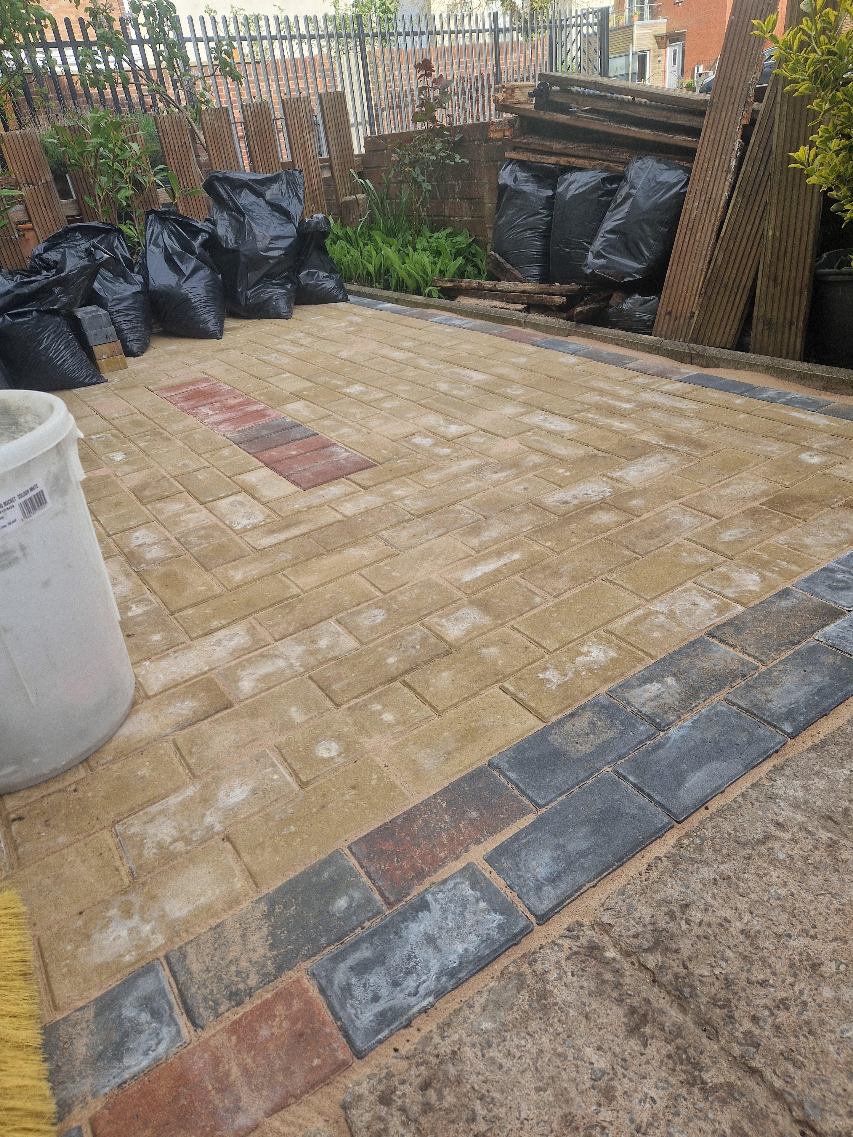 Patio paving in progress, with a contrasting dark border and access covers set into the paved area.